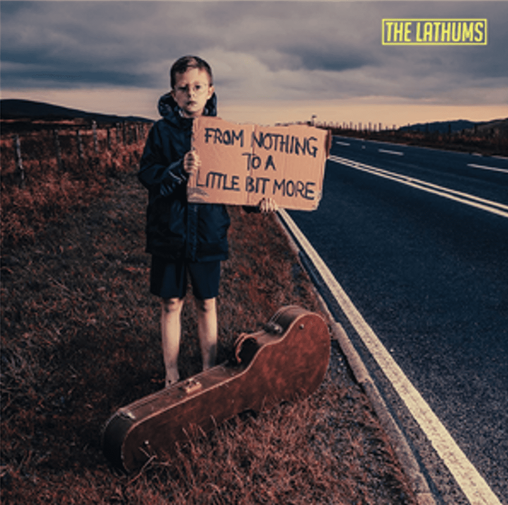 A young boy holding a sign next to a skateboard.